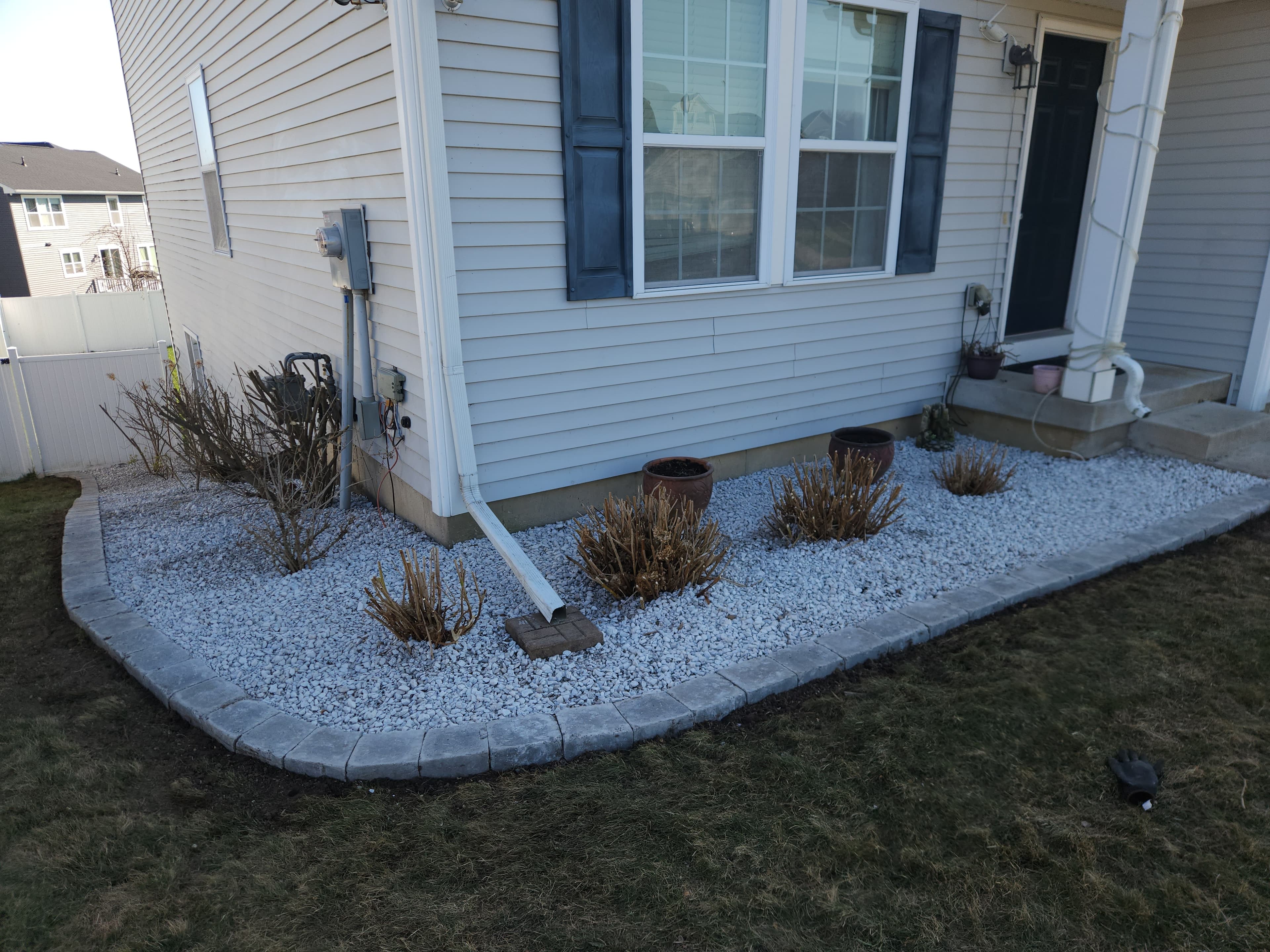 Paver-edged foundation bed of white rock and small shrubs along the front of a West Michigan home
