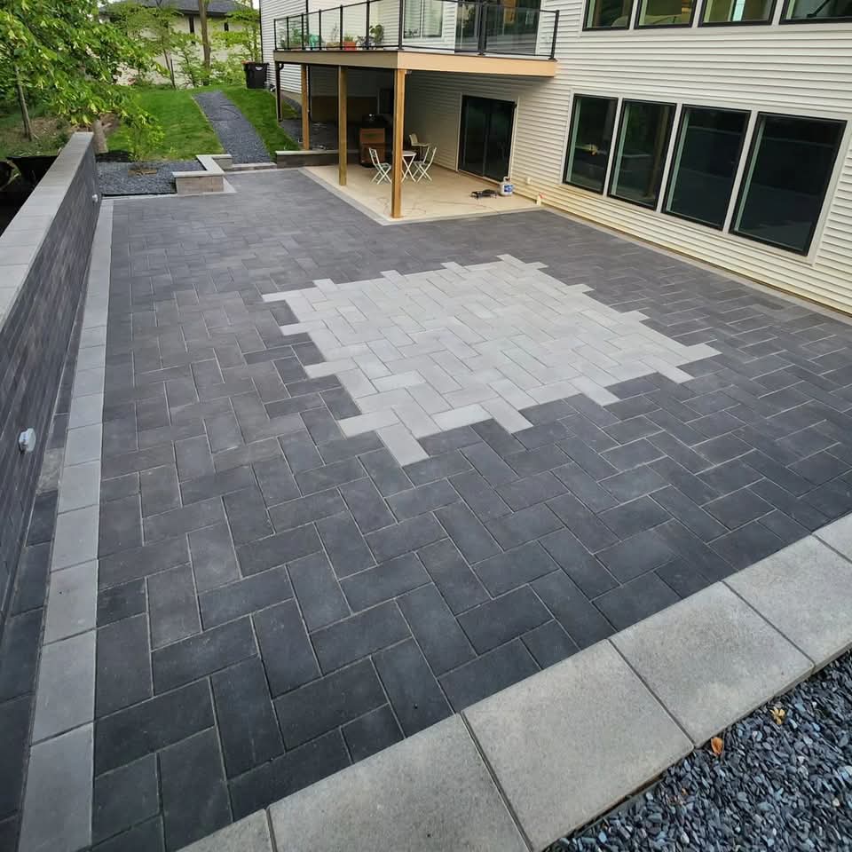 Large modern white and black farmhouse-style home at dusk with fresh green lawn, dark block planter beds with gravel and ornamental trees, and a concrete driveway