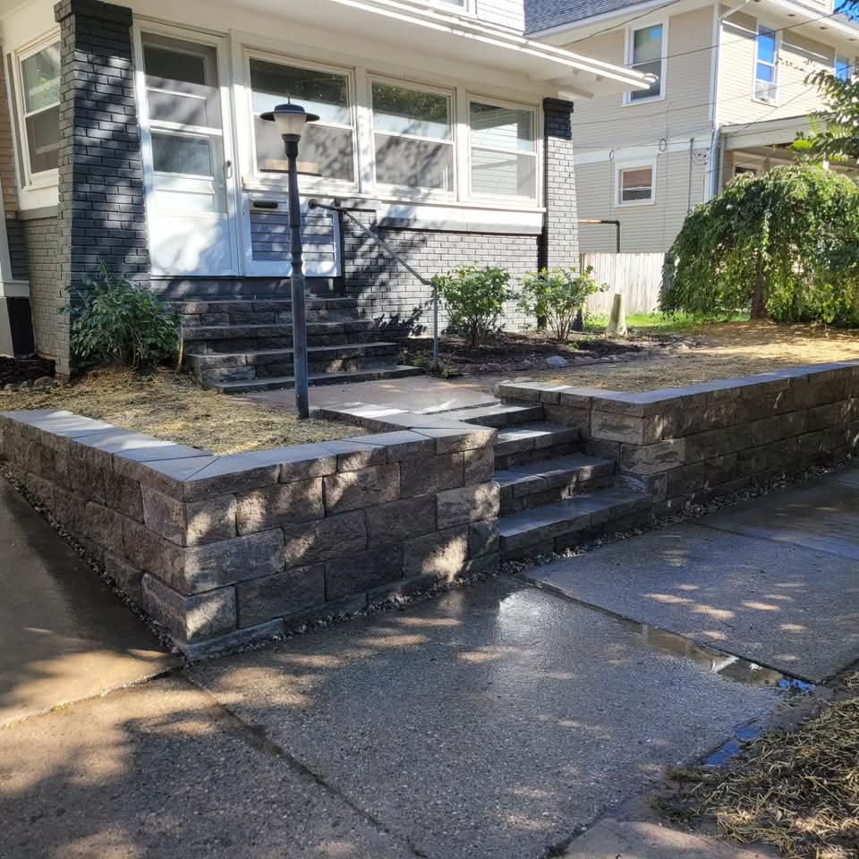 White vinyl privacy fence enclosing a residential backyard with old stone edging along the base, bare lawn, and a utility pole visible behind