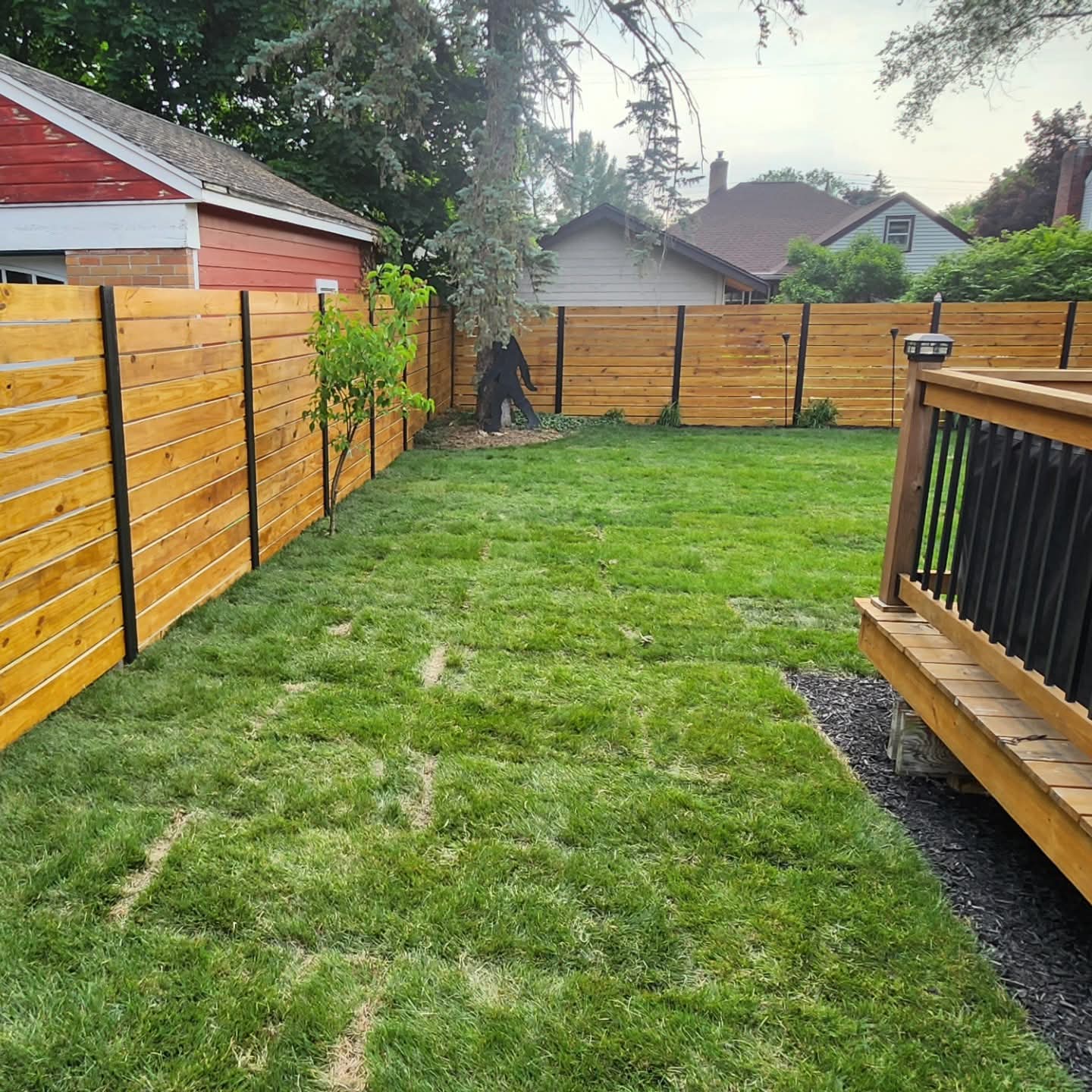 Backyard with freshly installed sod and a new horizontal-board wood privacy fence